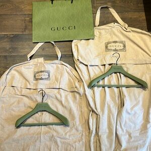 Two Gucci garment bags with hangers and green carry bag